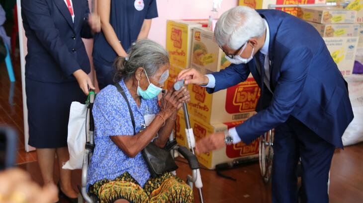 IFRC Secretary General Jagan Chapagain speaks to and assists a woman in a wheelchair in an eye clinic run by the Thai Red Cross Society in Bangkok, where she received medical support from staff and volunteers, in September 2022.