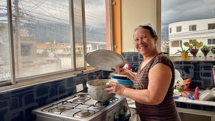 Belkis Colmenares sonríe a la cámara desde su cocina. Ella fue una de las personas migrantes que recibió ayuda en efectivo de la Cruz Roja Ecuatoriana para cubrir necesidades básicas como alimentos, alquiler y medicinas.  