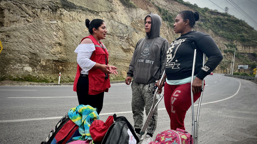 Cristia y Winston reciben información por parte de una voluntaria de la Cruz Roja Ecuatoriana.