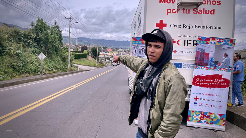 Yender delante de una Unidad Móvil de Salud de la Cruz Roja Ecuatoriana, señalando el largo camino que pronto recorrerá.